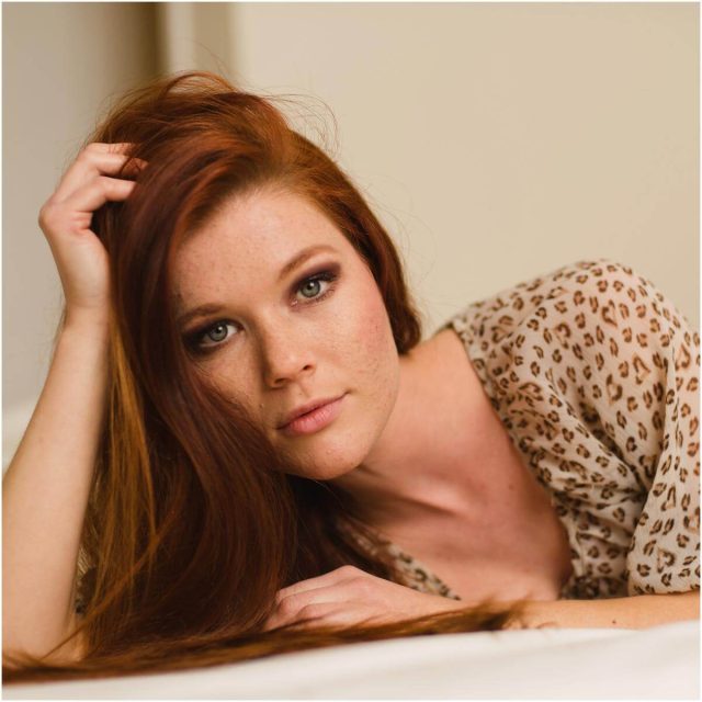 red hair girl leaning on bed