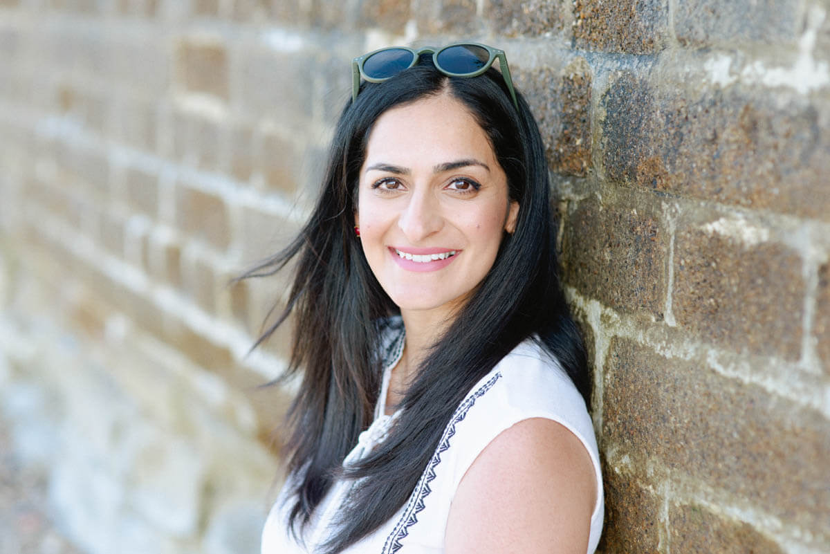 Smiling woman in professional attire standing by the sea wall, ideal for LinkedIn profile