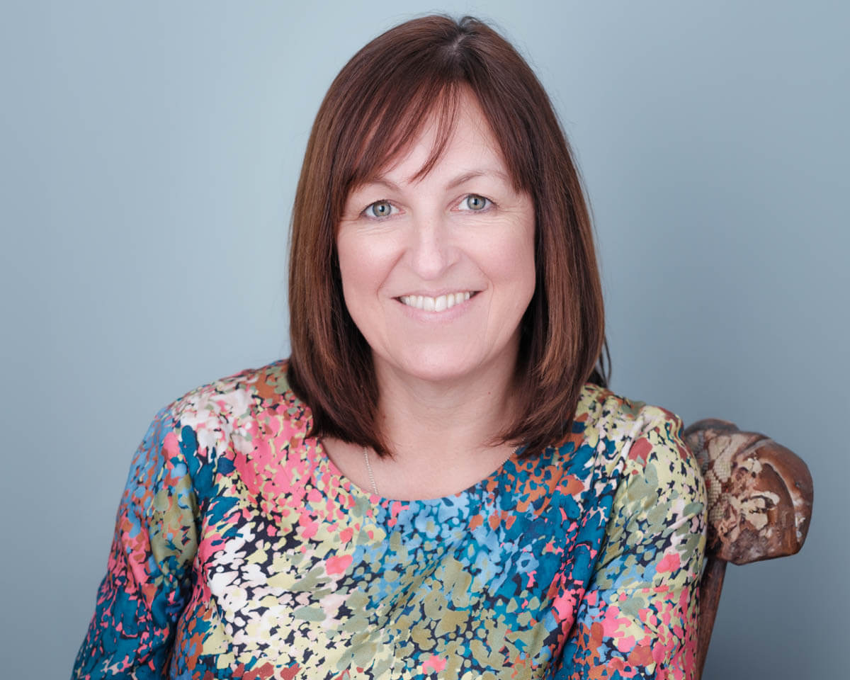 smiling older woman finance director bright top blue wall