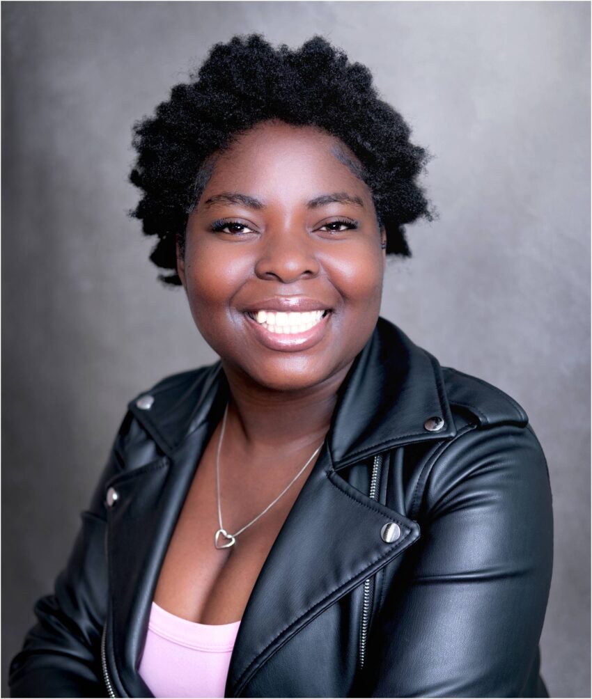 A vibrant headshot of a smiling black young woman, embodying youth and confidence in her stylish black leather jacket. Captured in the Isle of Wight.